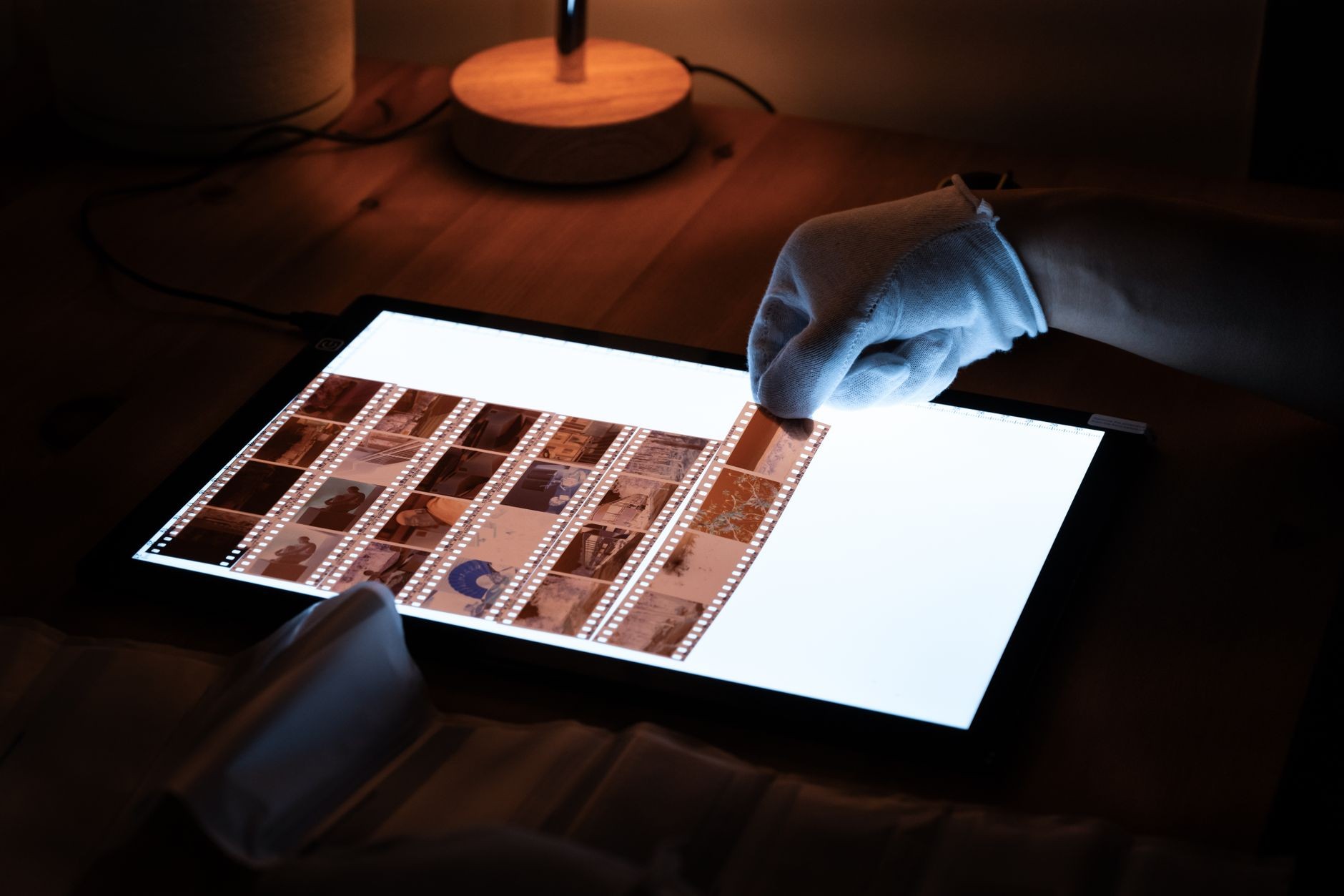 Négatifs manipulés avec précaution sur une table lumineuse avant numérisation